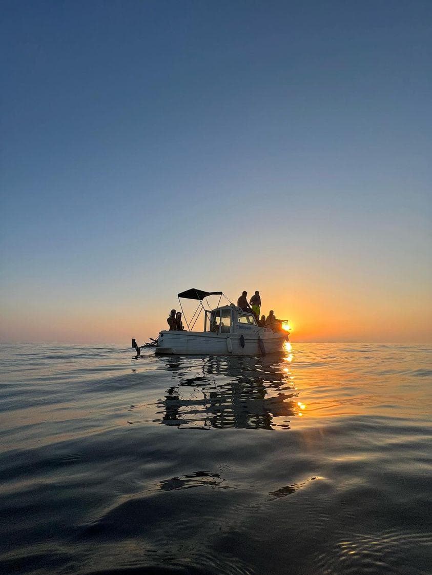 Big Blue Boat Trip boat on calm Adriatic water at sunset