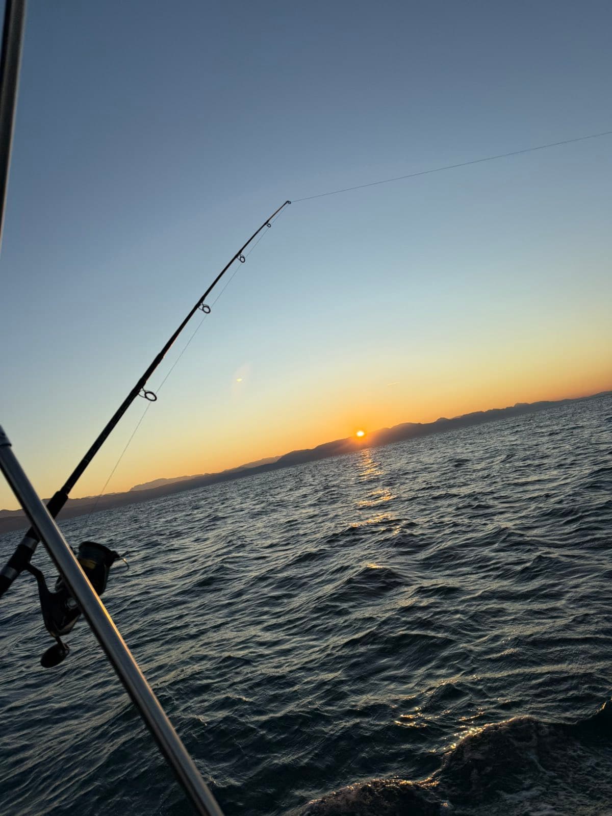 Fishing rod pointed toward the sunset over the Adriatic