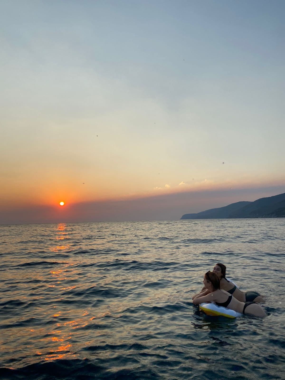 Guest sitting on a paddleboard at sunset