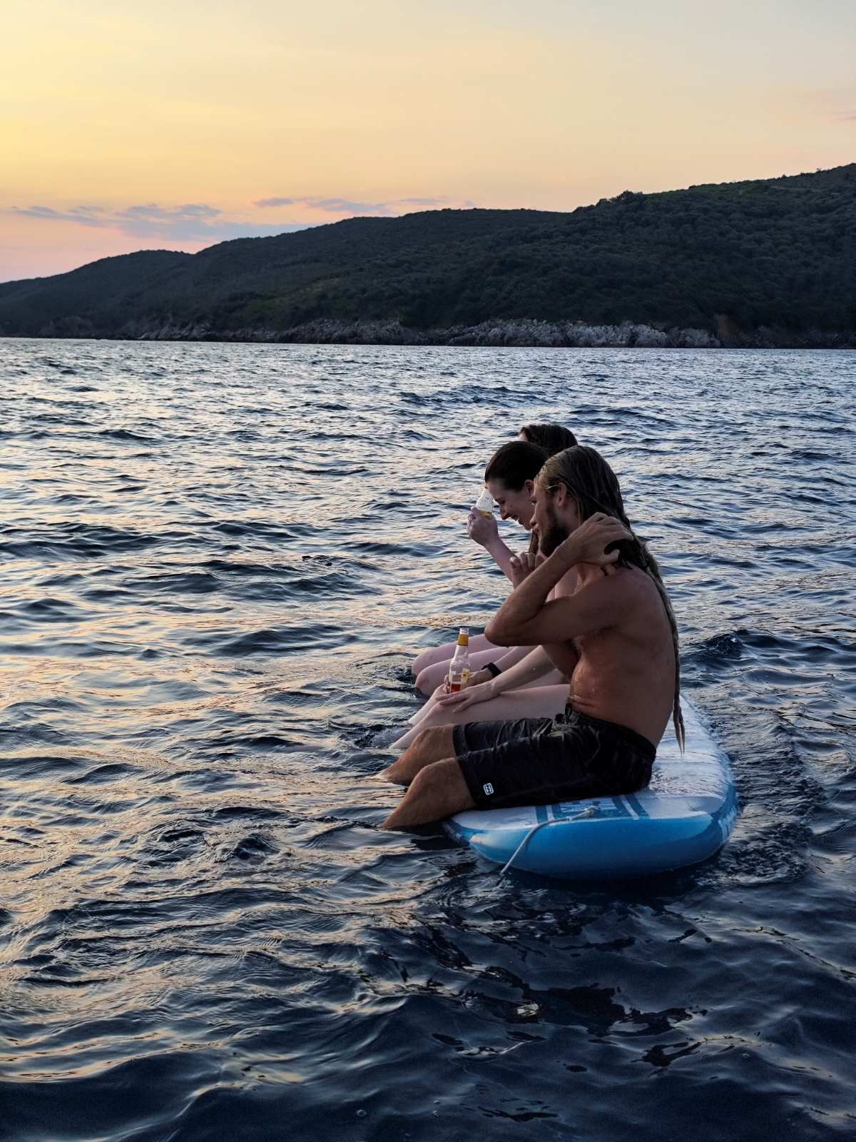 Guests relaxing on a paddleboard at dusk