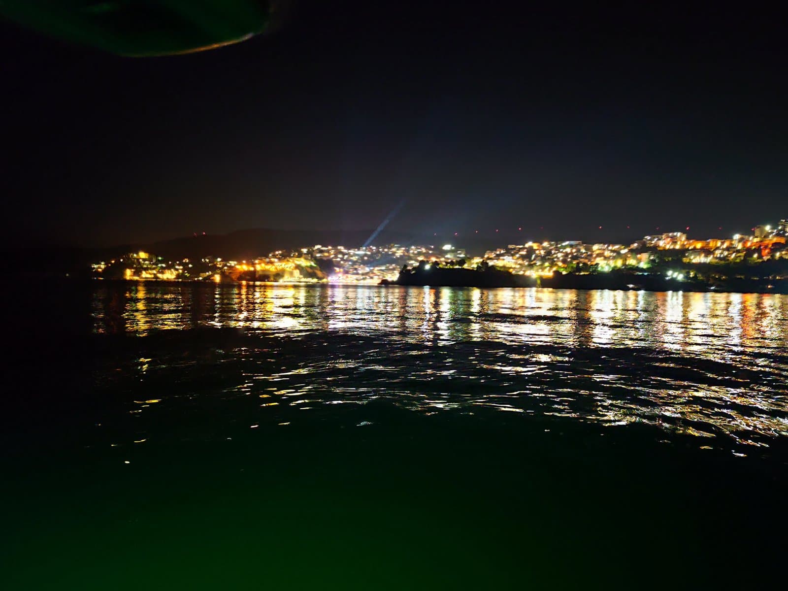 Night coastline lights mirrored on dark water