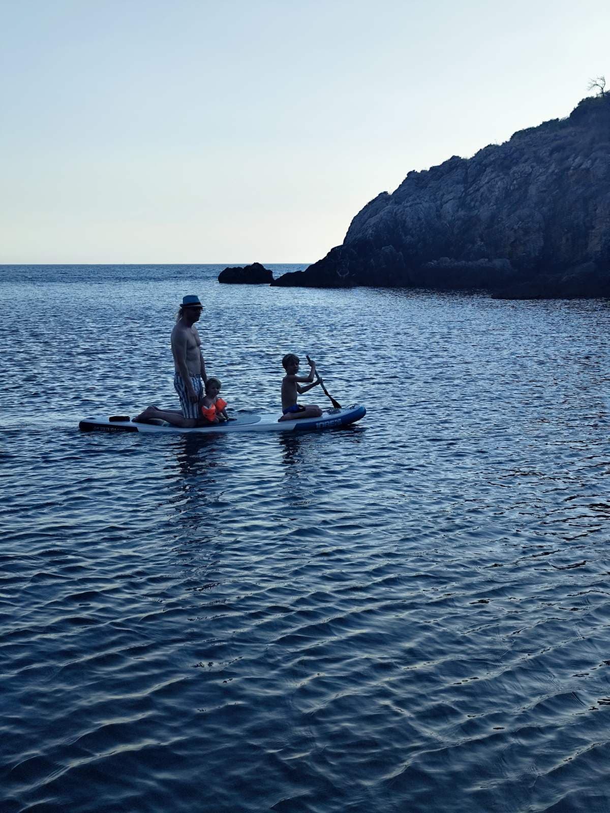 Paddleboarder crossing calm water near the cliffs